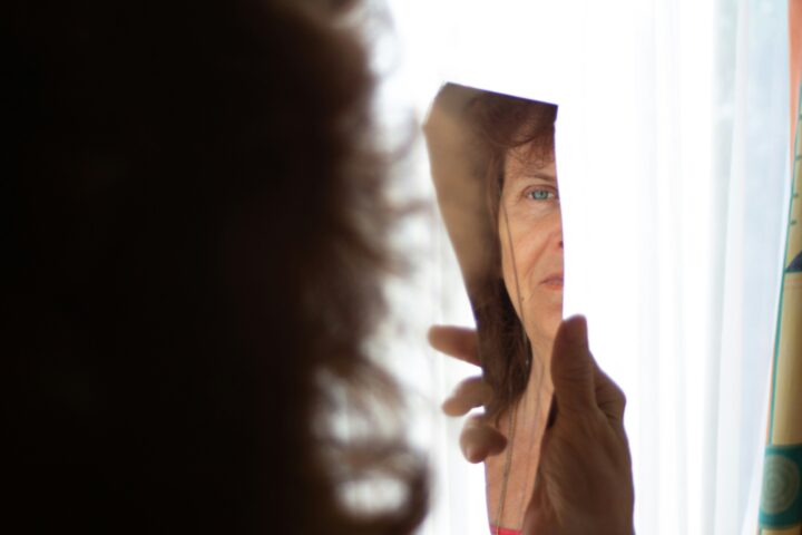 woman looks in broken mirror, struggling with body positivity