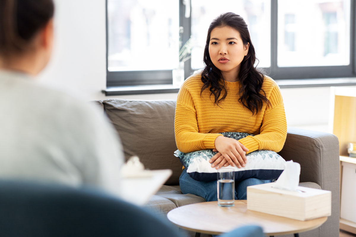 Young woman wearing yellow sweater talks to therapist in Beaverton office