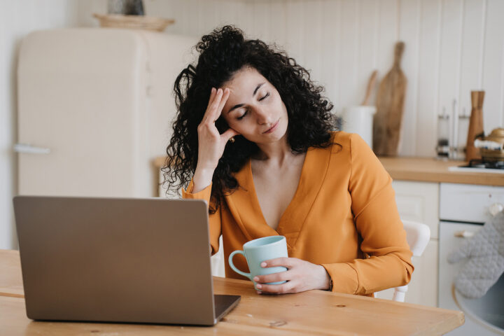 woman in Beaverton, OR experiencing burnout while sitting in front of a computer with her eyes closed
